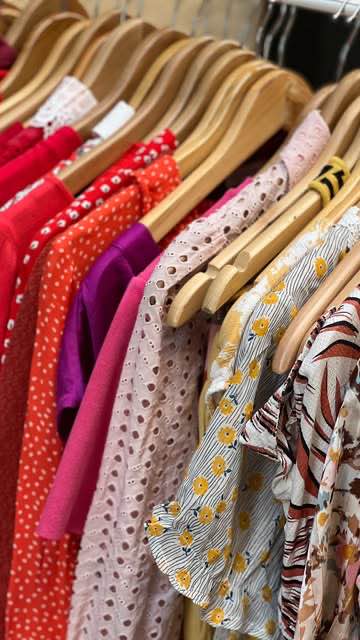 Portant de vêtements de seconde main colorés sur cintres en bois